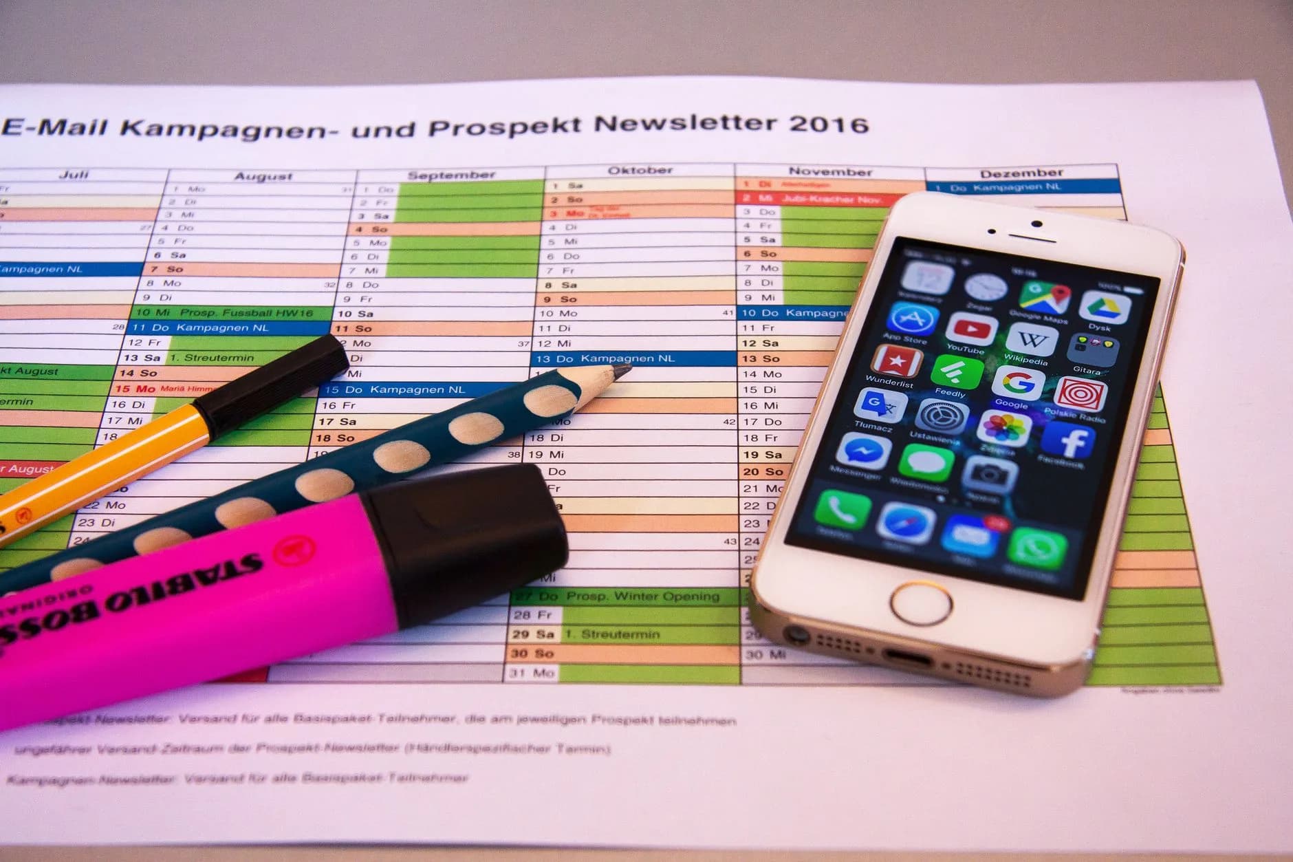 A desk setup featuring a planner, pens, and a smartphone displaying app icons, ideal for productivity.