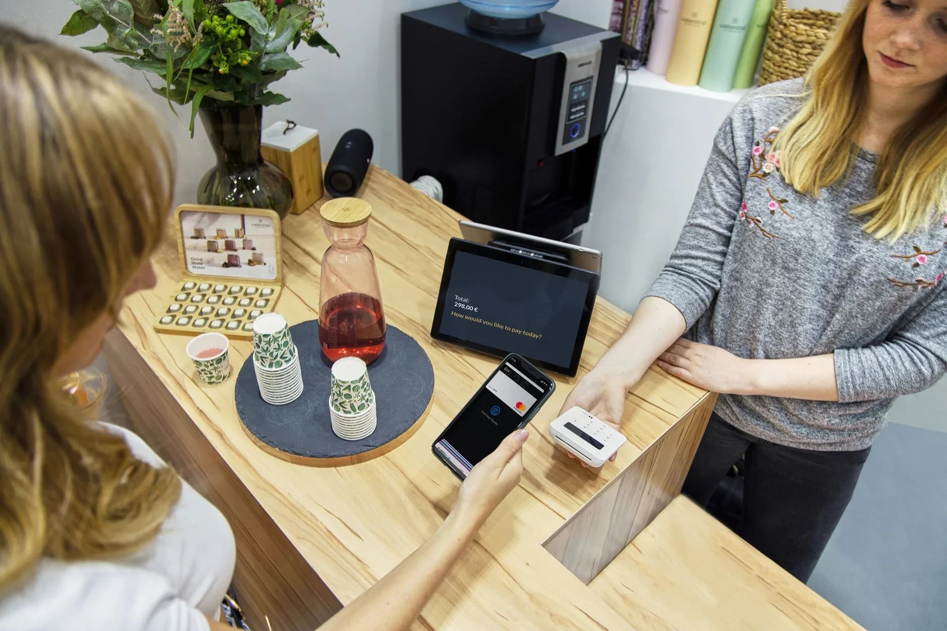 A woman makes a contactless payment at a stylish Berlin café, emphasizing technology and modern retail.