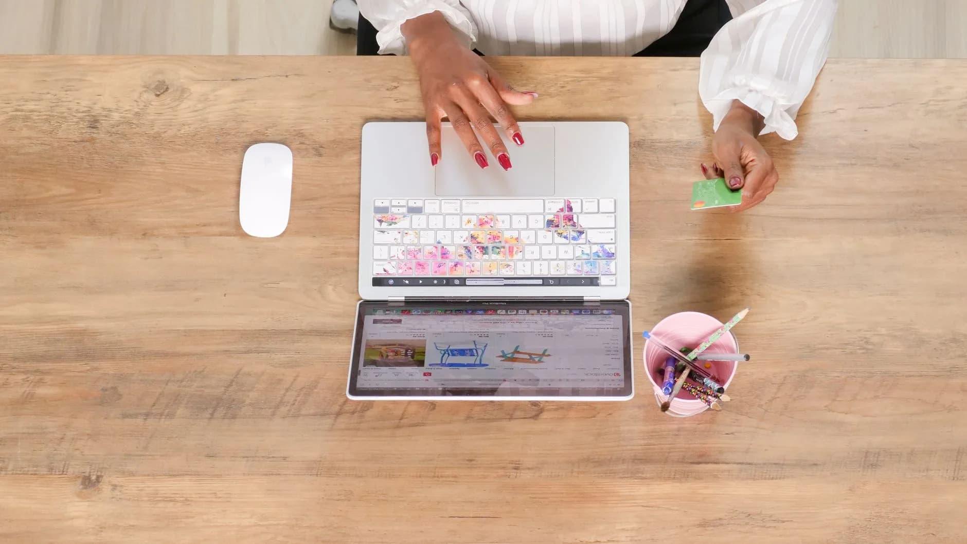 Female hand using a credit card while shopping online on a laptop from a top view angle.